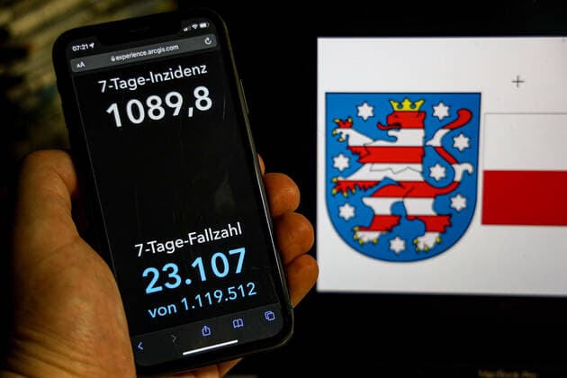 Coronavirus in Germany Covid 19 Dashboard of the Robert Koch Institute DEU, Germany, Thuringia 20 02 2022 The 7-day incidence for the state Cases last 7 days 100 000 p.e. is displayed on an iPhone, with the state coat of arms in the background.