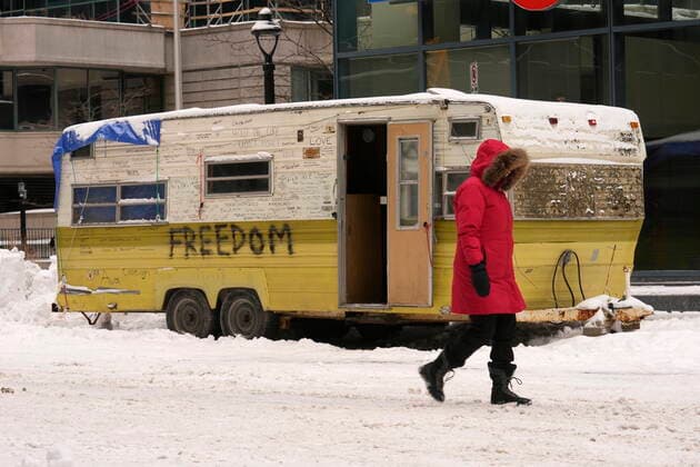 February 20, 2022, Ottawa, ON, Canada: A resident of Ottawa walks pass a camper trailer in downtown on Sunday, Feb. 20, 2022. A protest, which was first aimed at a COVID-19 vaccine mandate for cross-border truckers but also encompassed fury over the range of COVID-19 restrictions. Ottawa Canada  - ZUMAc35_ 20220220_zaf_c35_035 Copyright: xAdrianxWyldx