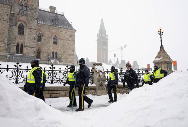 February 20, 2022, Ottawa, ON, Canada: Police officers walk pass the Parliament buildings in Ottawa on Sunday, Feb. 20, 2022. A protest, which was first aimed at a COVID-19 vaccine mandate for cross-border truckers but also encompassed fury over the range of COVID-19 restrictions. Ottawa Canada  - ZUMAc35_ 20220220_zaf_c35_041 Copyright: xAdrianxWyldx