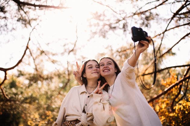 IMAGO Creative, Jahreszeit Herbst, Ferien Happy girlfriends taking selfie standing in park in autumn CR_DMBE220219-918537-01 ,model released, Symbolfoto