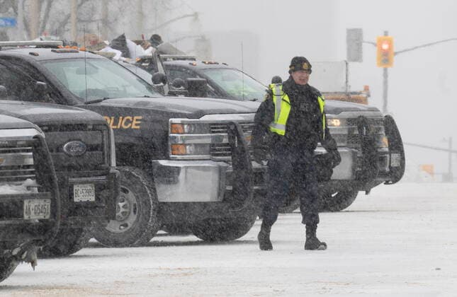 February 20, 2022, Ottawa, ON, Canada: An officer stands next to police vehicles are parked downtown Ottawa on Sunday, Feb. 20, 2022. A protest, which was first aimed at a COVID-19 vaccine mandate for cross-border truckers but also encompassed fury over the range of COVID-19 restrictions. Ottawa Canada  - ZUMAc35_ 20220220_zaf_c35_050 Copyright: xAdrianxWyldx