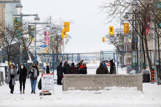 February 20, 2022, OTTAWA, ON, CANADA: People stand outside of a fenced off portion of downtown Ottawa on Sunday, Feb. 20, 2022, after police worked to clear a trucker protest that was aimed at COVID-19 measures before growing into a broader anti-government protest. OTTAWA CANADA  - ZUMAc35_ 20220220_zaf_c35_064 Copyright: xColexBurstonx