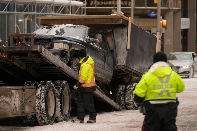 February 20, 2022, Ottawa, ON, Canada: Police looks on as a tow truck operator readies a truck to be removed from downtown Ottawa on Sunday, Feb. 20, 2022. A protest, which was first aimed at a COVID-19 vaccine mandate for cross-border truckers but also encompassed fury over the range of COVID-19 restrictions. Ottawa Canada  - ZUMAc35_ 20220220_zaf_c35_065 Copyright: xAdrianxWyldx