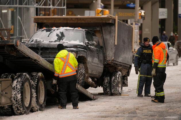 February 20, 2022, Ottawa, ON, Canada: A police officer speaks tow truck operators as truck is being removed from downtown Ottawa on Sunday, Feb. 20, 2022. A protest, which was first aimed at a COVID-19 vaccine mandate for cross-border truckers but also e ancompassed fury over the range of COVID-19 restrictions. Ottawa Canada  - ZUMAc35_ 20220220_zaf_c35_066 Copyright: xAdrianxWyldx