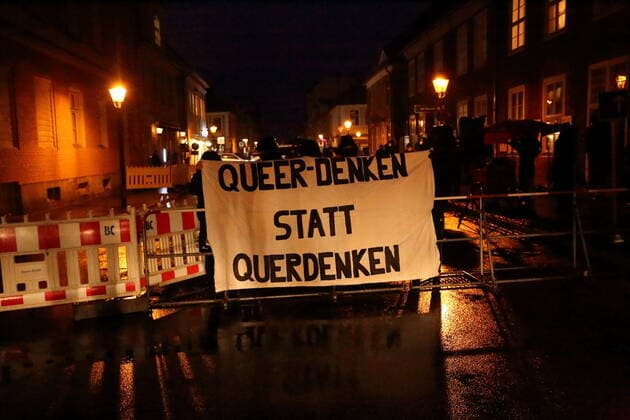 Counter demonstrators stand with banner Queer denken statt querdenken in Gutenbergstraße during a demonstration against compulsory vaccination in the coronavirus pandemic, Potsdam, Germany, February 21, 2022 Demo gegen Impfpflicht