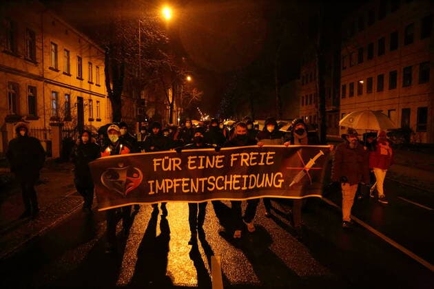 Demonstrators walk with banner For a free vaccination decision in Jägerallee during a demonstration against compulsory vaccination in the coronavirus pandemic, Potsdam, Germany, Feb. 21, 2022 Demo against compulsory vaccination