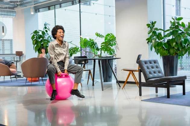 IMAGO Creative: Business - Progressive Geschäftsmodelle Cheerful businesswoman sitting on hopper ball in lobby model released property released, EIF03081