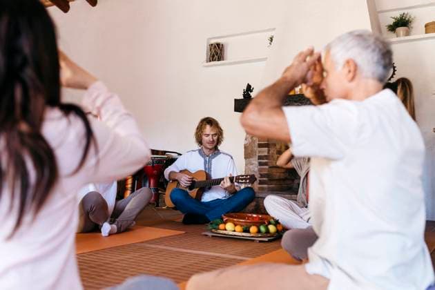 Musician playing guitar and friends meditating together in farmhouse model released property released, JRFF05296