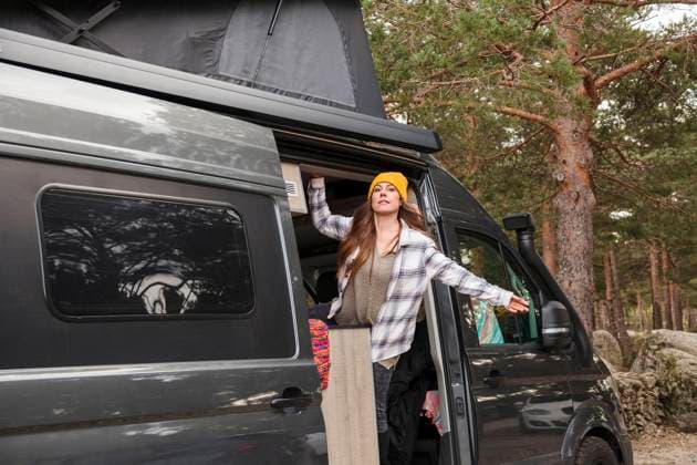 IMAGO Creative: Herbst, Touren mit dem Camper Woman standing with arm outstretched at doorway of van model released, MRRF01862