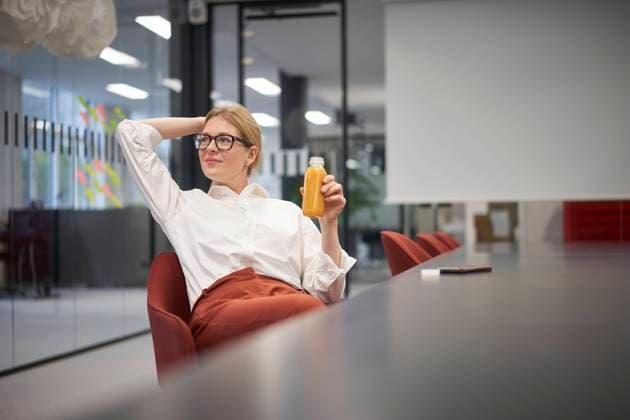 Businesswoman with juice bottle sitting in office model released property released, JAHF00152