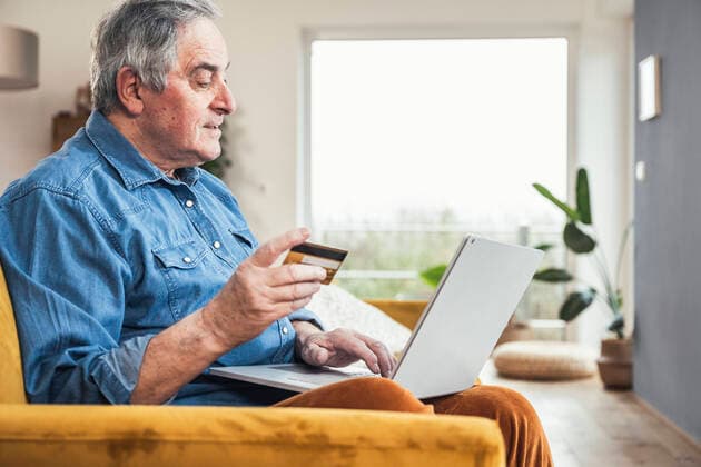 IMAGO Creative: Digitale Welt, Social Commerce Senior man with credit card making online payment through laptop in living room model released property released, UUF25351