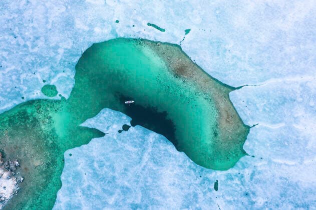 IMAGO Creative, Winter, Winterspaß, Eishockey Germany, Bavaria, Aerial view of lone man paddleboarding between ice floes in turquoise Eibsee lake model released, Grainau Bayern Deutschland Eibsee WFF00687