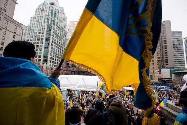 February 26, 2022, Vancouver, British Columbia, Canada: A person waves a Ukrainian flag over the crowd at a rally supporting Ukraine. Vancouver Canada  - ZUMA Pho 20220226_mda_w171_188 Copyright: xRyanxWalterxWagnerx