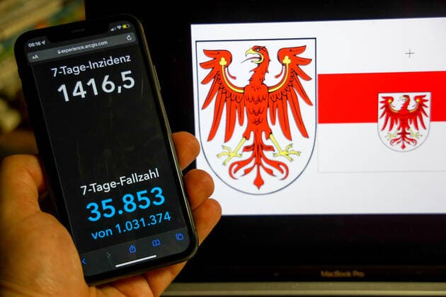 Coronavirus in Germany Covid 19 Dashboard of the Robert Koch Institute DEU, Germany, Brandenburg 27 02 2022 The 7-day incidence for the state Cases last 7 days 100 000 p.e. is displayed on an iPhone, with the states coat of arms in the background