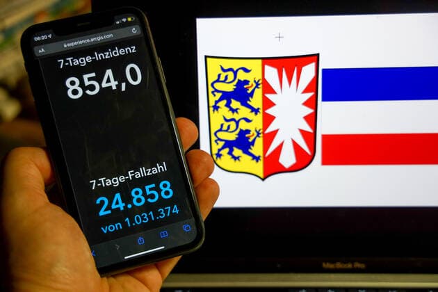 Coronavirus in Germany Covid 19 Dashboard of the Robert Koch Institute DEU, Germany, Schleswig Holstein 27 02 2022 The 7-day incidence for the state Cases last 7 days 100 000 p.e. is displayed on an iPhone, in the background the state coat of arms