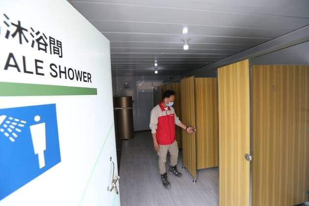 (220302) -- HONG KONG, March 2, 2022 -- A staff member checks shower rooms at the community isolation facility (CIF) in Tsing Yi, south China s Hong Kong, March 2, 2022. A newly built CIF started admitting its first batch of COVID-19 patients in Hong Kong on Tuesday evening. The facility, located in Tsing Yi, is open for service one day after its construction was completed within just one week on Monday with the support of the mainland. The CIF, with the capacity of accommodating about 3,900 patients, is a combination of modular cubicles, with each room equipped with basic furniture and bedding, air conditioner, smoke detector, and fire extinguisher. ) CHINA-HONG KONG-ISOLATION FACILITY (CN) WanxHoude