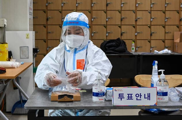 An health worker hands out plastic gloves to voters in the Seochon neighborhood of Seoul, South Korea during the presidential election on Wednesday, March 9, 2022. The election is taking place in the midst of the country s largest-ever COVID-19 outbreak.  SEO2022030918 THOMASxMARESCA