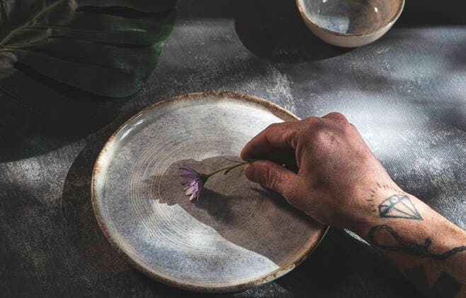 Creative Highlights Symbolbilder High angle of crop anonymous tattooed male placing blooming flower on round ceramic plate JordiCalvera_Homenature_4.jpg Copyright: xJordixCalverax Model Released