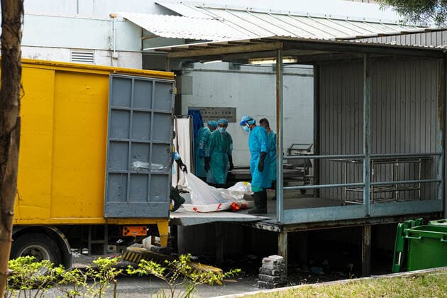 March 18, 2022, Hong Kong, China: Workers with PPE transport bodies to a truck at a public mortuary. Hong Kong health authorities have set up refrigerated shipping containers outside a public mortuary to store dead bodies as mortuaries and hospitals are running out of space. Hong Kong China - ZUMAt141 20220318_zap_t141_003 Copyright: xKeithxTsujix