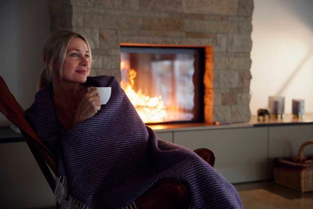 IMAGO Creative: Herbst, Gemütliches Zuhause Woman wrapped in blanket holding coffee cup sitting in living room model released property released, RBF08531