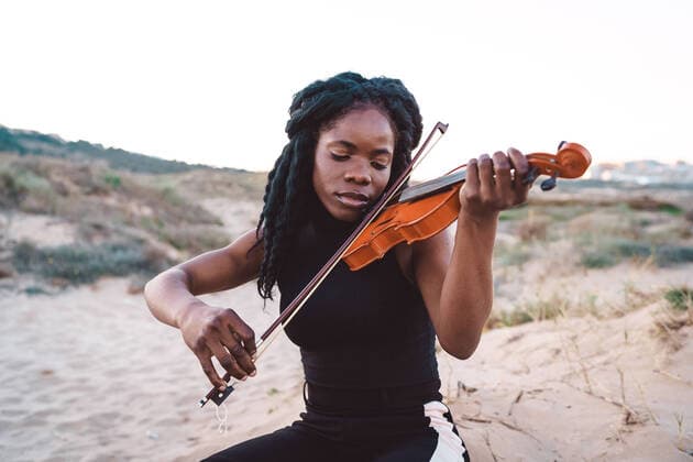 Creative Highlights Symbolbilder Serene African American female musician playing melody on violin while enjoying music with closed eyes on sandy beach, Model released OscarDeDios_LifestyleCrisAndSlivia_26.jpg Copyright: xOscarxDexDiosx MR