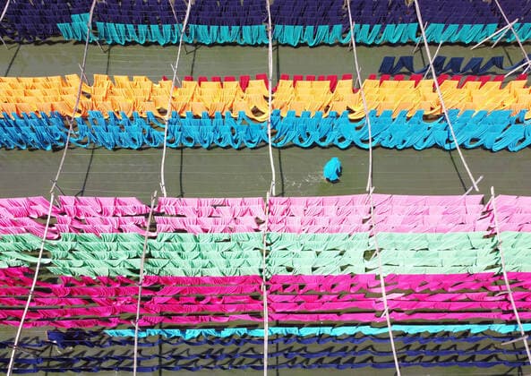 IMAGO Nature: Unsere Erde, Klimawandel, Baumwolle Colorful Fabrics Production Factory NARAYANGANJ, BANGLADESH - APRIL 5, 2022: Aerial photo taken with a drone of Workers hanging thousands of different coloured fabrics to dry it, on flooded field during the final part of the dying process in a fabric factory. The cloths are dyed using machines and laid out in nearby fields as it is cheaper and more sustainable to dry them out in sunlight for to 6 hours, to can start manufacturing of clothes. On April 5, 2022 in Narayanganj, Bangladesh. (Photo by Joy Saha Eyepix Group) Copyright: xJoyxSahax xEyepixxGroupx EYEPIX_JS_05042022_59640