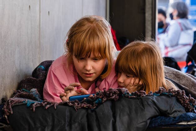 Children from Ukraine look at a phone while staying at a makeshift camp near the San Ysidro Port of Entry of the U.S.-Mexico border on Monday, April 4, 2022 in Tijuana, Mexico. The refugees are given a number so they do not have to wait in line as the United States said they will accept 100,000 Ukrainian refugees due to the Russian invasion of Ukraine.  MEX20220404061 ARIANAxDREHSLER