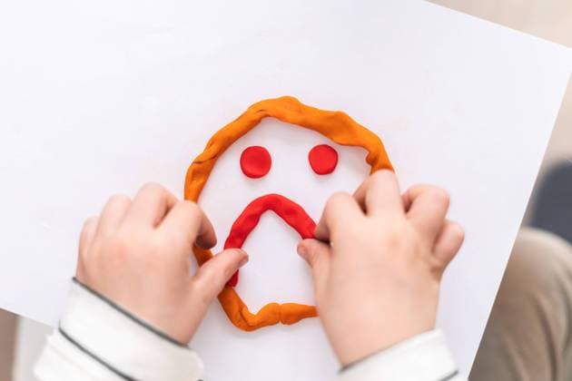 Top view hand of crop unrecognizable child making sad face made of red plasticine on white paper, Model released, Property released AngelSantamaria_PsychologicalHelp_29.jpg Copyright: xAngelxSantamariax MR