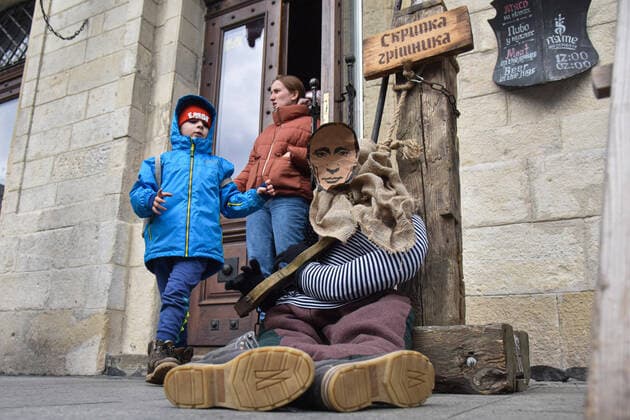 April 3, 2022, Lviv, Ukraine: A boy looks at a mannequin of a medieval prisoner with a portrait of Russian President Vladimir Putin at the entrance to a cafe. Due to Russia s military invasion of Ukraine, a mannequin of a medieval prisoner with the head of the occupying power, President Vladimir Putin, placed in medieval torture - the sinner s violin - was placed near Lviv cafe Lviv Ukraine - ZUMAs197 20220403_zaa_s197_401 Copyright: xPavloxPalamarchukx