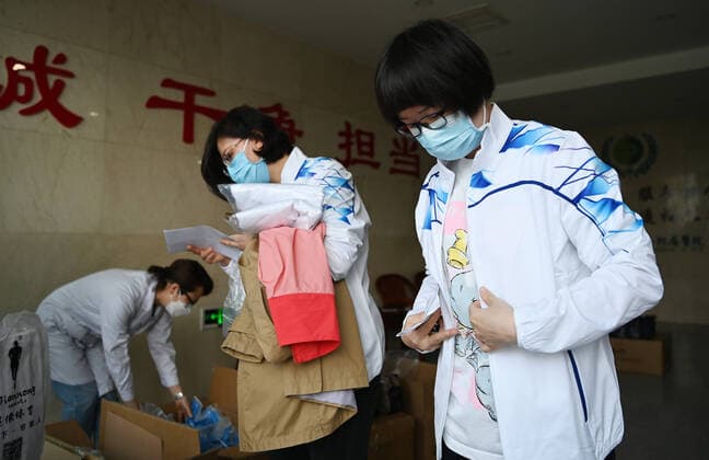 Coronavirus, Eindrücke aus China (220411) -- TIANJIN, April 11, 2022 -- Xu Ning (1st R) puts on team uniform before leaving for Shanghai, in north China s Tianjin, April 11, 2022. Tianjin sent a team of 78 traditional Chinese medicine (TCM) medical workers to help Shanghai fight COVID-19 pandemic on Monday. Xu Ning, a deputy chief physician from the First Teaching Hospital of Tianjin University of Traditional Chinese Medicine, is one of them. Over the past two years, she has been in the wards of Tianjin Haihe Hospital for many times to fight against the pandemic, and gained a lot of experience in TCM treatment. ) CHINA-TIANJIN-TCM-MEDICAL TEAM-SHANGHAI-AID (CN) LixRan