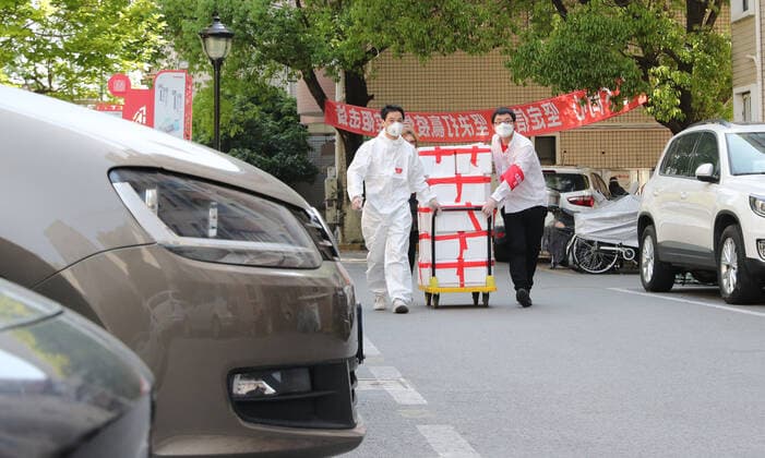 (220412) -- SHANGHAI, April 12, 2022 -- Shi Zhongliang (L) delivers parcels for residents under temporary closed-off management in east China s Shanghai, April 11, 2022. Shi Zhongliang, a resident of Qibao Township, Minhang District of Shanghai, now renders his service as a volunteer in his community. His residential community has been under closed-off management since March 18 due to the resurgence of COVID-19. Soon after that, Shi joined the community volunteer team spontaneously organized by the residents from the same community. The team, with only seven members from the start, has grown as big as 40 within a month. Shi and his teammates are mainly responsible for delivering the living materials purchased online by the resident