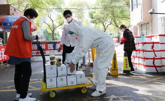 (220412) -- SHANGHAI, April 12, 2022 -- Shi Zhongliang (2nd R) loads the disinfected living materials onto a cart for delivery in east China s Shanghai, April 11, 2022. Shi Zhongliang, a resident of Qibao Township, Minhang District of Shanghai, now renders his service as a volunteer in his community. His residential community has been under closed-off management since March 18 due to the resurgence of COVID-19. Soon after that, Shi joined the community volunteer team spontaneously organized by the residents from the same community. The team, with only seven members from the start, has grown as big as 40 within a month. Shi and his teammates are mainly responsible for delivering the living materials purchased online by the residents