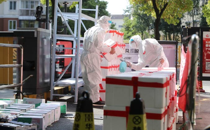 (220412) -- SHANGHAI, April 12, 2022 -- Shi Zhongliang (R) sprays disinfectants on newly-arrived parcels at the entrance of his residential community in east China s Shanghai, April 11, 2022. Shi Zhongliang, a resident of Qibao Township, Minhang District of Shanghai, now renders his service as a volunteer in his community. His residential community has been under closed-off management since March 18 due to the resurgence of COVID-19. Soon after that, Shi joined the community volunteer team spontaneously organized by the residents from the same community. The team, with only seven members from the start, has grown as big as 40 within a month. Shi and his teammates are mainly responsible for delivering the living materials purchased