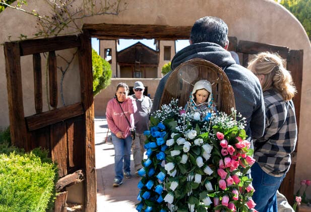 April 15, 2022, USA: David Gallegos, from Albuquerque, carries a basket with a figure of the Virgin Mary as he waits to enter the Santuario de Chimayo after his Good Friday Pilgrimage, Friday April 15, 2022. Gallegos has carried this basket on his pilgrimage for 25 years, he only changes the flowers each year. The red and blue roses represent the girls and boys who have died due to vilonce and the white is for their purity. USA - ZUMAab1_ 20220415_zaf_ab1_027 Copyright: xEddiexMoorex