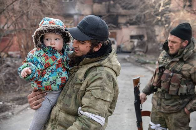 April 15, 2022, Mariupol, Ukraine: Chechen fighter poses with a baby at a humanitarian aid distribution close to the frontline in Eastern Mariupol. The battle between Russian Pro Russian forces and the defending Ukrainian forces led by the Azov battalion continues in the port city of Mariupol. Mariupol Ukraine - ZUMAs197 20220415_zaa_s197_340 Copyright: xMaximilianxClarkex