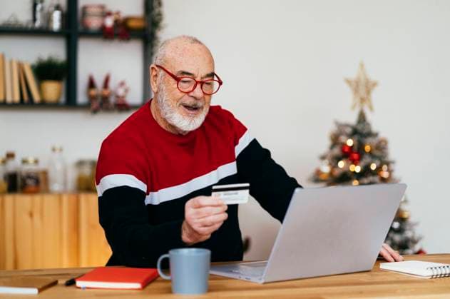 Senior man holding credit card doing online shopping through laptop at home model released, Symbolfoto property released, GIOF15359