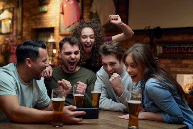 Group of cheerful soccer fans having beer and watching a match on smartphone in a pub model released, Symbolfoto property released, ABIF01683
