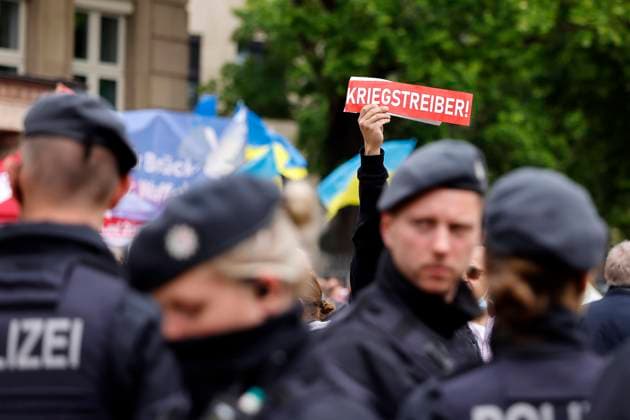 Ein Demonstrant gegen Kanzler Olaf Scholz hält ein Plakat mit dem Wort Kriegstreiber! über eine Reihe von Polizisten in die Höhe auf der DGB-Veranstaltung am Tag der Arbeit auf dem Johannes Rau Platz. Düsseldorf, 01.05.2022 NRW Deutschland *** A demonstrator against Chancellor Olaf Scholz holds up a placard with the word war monger over a line of police officers at the DGB Labor Day event at Johannes Rau Platz Düsseldorf, 01 05 2022 NRW Germany Copyright: xChristophxHardtx