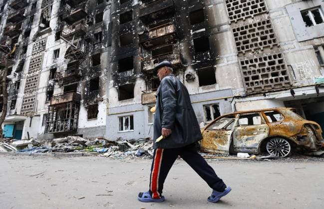 DONETSK REGION, UKRAINE - MAY 5, 2022: A local man walks past an apartment building damaged by shelling in the embattled city of Mariupol. With tension escalating in Donbass in February, the Russian Armed Forces launched a special military operation in Ukraine in response to appeals for help from the Donetsk and Lugansk People s Republics. Peter Kovalev TASS  TS12FC10