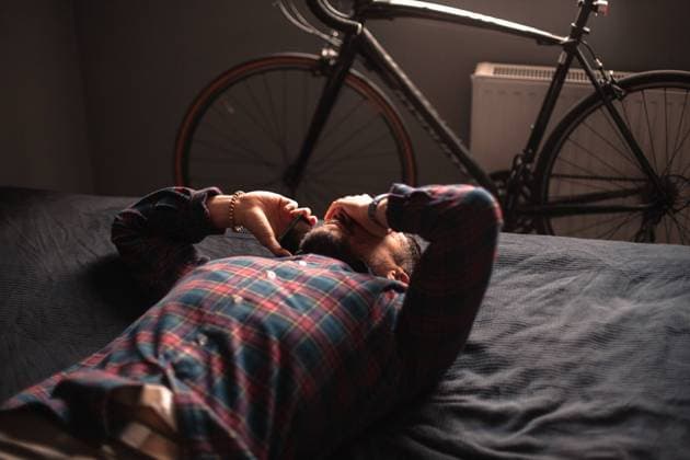 Exhausted man talking on smart phone lying on bed at home New York, New York, United States CR_DMBE211029-835026-01 ,model released, Symbolfoto