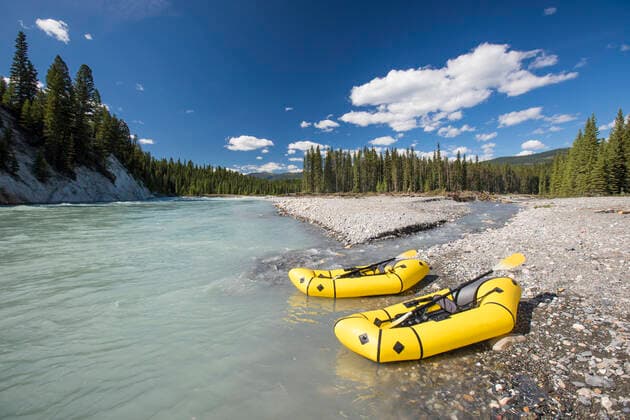 Two inflatable rafts on rocky shore next to river. Kootenay Crossing, British Columbia, Canada CR_JDIP211018-840339-01