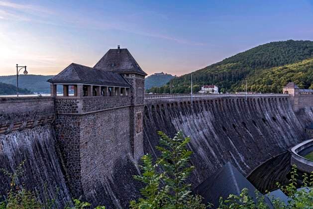 IMAGO Nature: Unsere Erde, Energiequellen, Wasserkraft  Staudamm, Torhäuser auf Sperrmauer von Stausee Edersee, Talsperre Edertal, Edertalsperre, Hotel Ederseeblick, hinten Schloss Waldeck, Sonnenuntergang, blaue Stunde, Edertal, Kassel, Hessen, Deutschland, Europa *** Dam, Torhäuser at Barrier wall from Reservoir Edersee, Dam eder valley, Edertalsperre, Hotel Edersee view, at the back Castle Waldeck, Sunset, Blue Hour, eder valley, Kassel, Hesse, Germany, Europe Copyright: imageBROKER/RaimundxKutter iblrai08301784.jpg