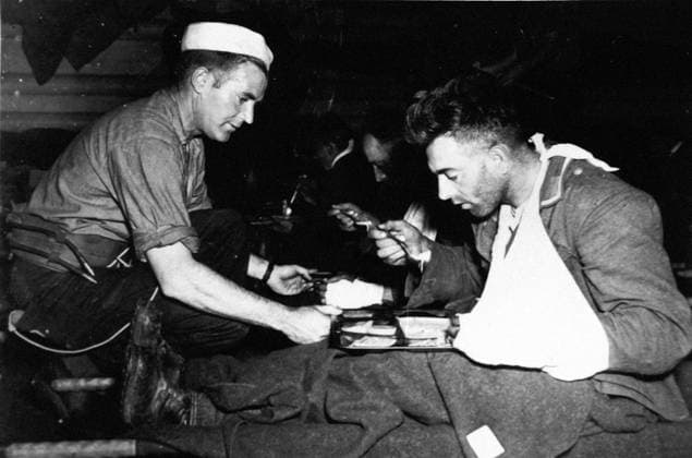 U.S sailor aids German prisoner (June 1944 after D-Day) A U.S Navy pharmacist s mate helps a wounded German soldier taken prisoner in France to eat aboard a landing ship carrying prisoners to camps in England (June 1944) Copyright: xPhoto12 Coll-DITE USISx DIT01037_087