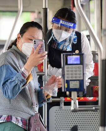 (220522) -- SHANGHAI, May 22, 2022 -- A passenger (L) shows her negative result certificate for nucleic acid testing on a bus in Shanghai, east China, May 22, 2022. Shanghai started to resume cross-district public transport starting from Sunday. Transport service on four subway lines and 273 bus routes has resumed on Sunday covering the central urban areas and the city s airports, railway stations, and hospitals. Passengers are allowed to use the public transport system only when they have negative result certificates for nucleic acid testing taken within 48 hours. ) CHINA-SHANGHAI-PUBLIC TRANSPORTATION-RESUMPTION (CN) LixHe 
