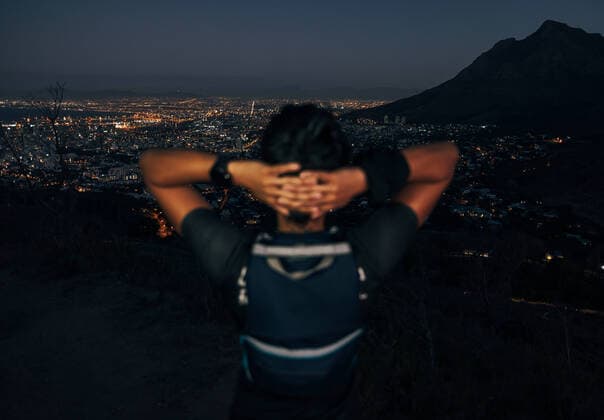 Unrecognizable woman hiker enjoying the view of a night city from mountain Copyright: xArtemxVarnitsinxArtemxVarnitsinx