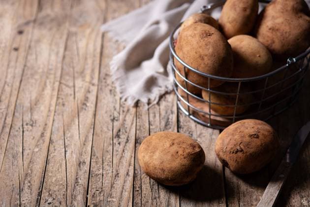 High angle of raw potatoes placed on wooden table in kitchen Copyright: xEstefaniaxTorresx Model Released
