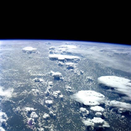 (5-13 Oct 1984) --- Flatirons , cumulonimbus clouds that have flattened out at a high altitude, the result of rapidly rising moist air. At a given altitude, depending on the temperature, wind, and humidity, the cloud mass can no longer rise and the wind aloft shears the cloud. Central Nigeria, an area in which tropical rain forest gives way to dryer savannah lands, lies beneath a layer a heavy haze and smoke. 1062_36_M_-11390-