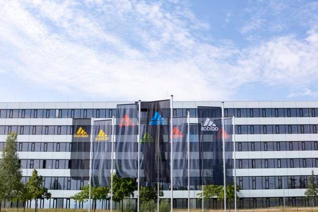 Die Firmenzentrale des Sportartikelherstellers adidas in Herzogenaurach Bunte Fahnen vor dem Gebäude Laces Symbolbild Illustration Herzogenaurach Bayern Deutschland *** The headquarters of the sporting goods manufacturer adidas in Herzogenaurach Colorful flags in front of the building Laces Symbol Image Illustration Herzogenaurach Bavaria Germany