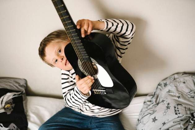 Portrait of boy with down syndrome holding guitar sitting in bedroom Sweden, Gothenburg, model released, property released Copyright: xMaskotx , MA93751