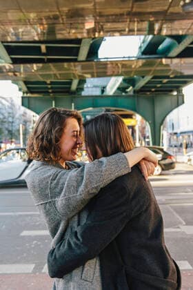 Cheerful Lesbian couple embracing while standing on street under bridge in city Germany, Berlin, model released Copyright: xMaskotx , MA94164